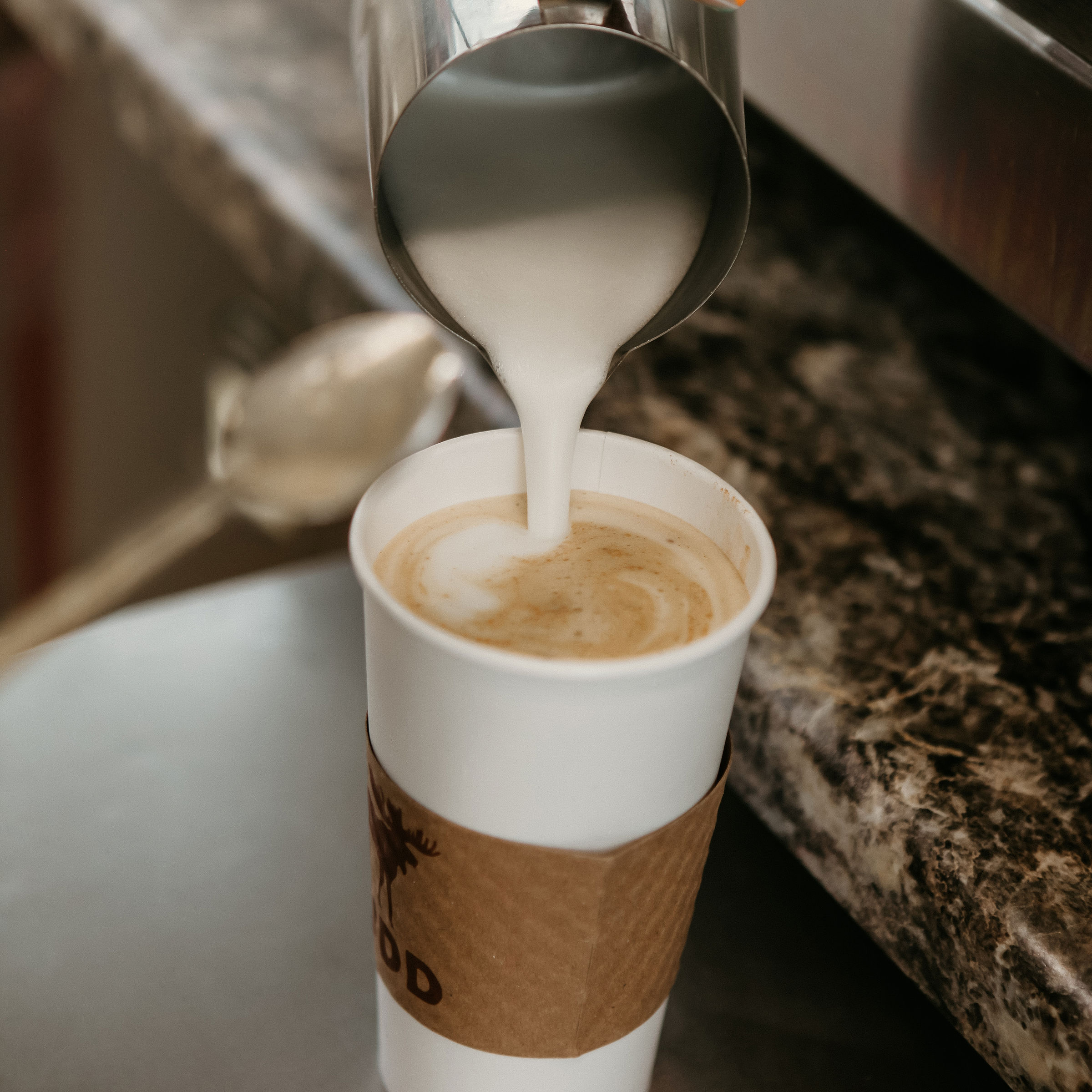 Pouring frothed milk into cup